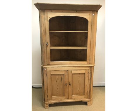 A 19th Century pine free-standing corner cabinet, the single formerly glazed door enclosing two shelves over two cupboard doo