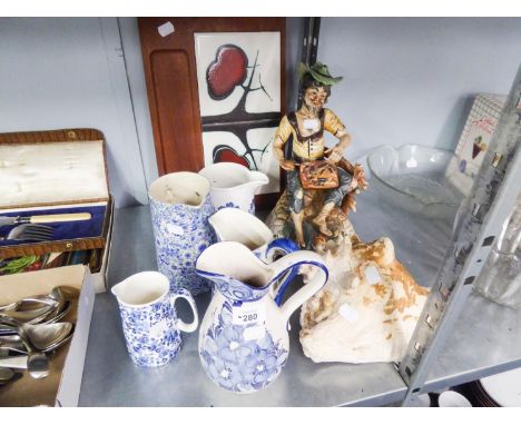 FIVE VARIOUS BLUE AND WHITE POTTERY JUGS, A LARGE ITALIAN POTTERY SEATED FIGURE OF A TRAMP, A LARGE CONCH SHELL, AND A TEAK C