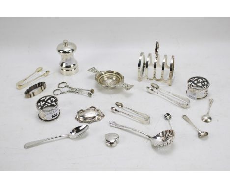 An assortment of silver, 19th century and later. Including a toast rack, sugar tongs, a strainer, a Claret label, a pair of p