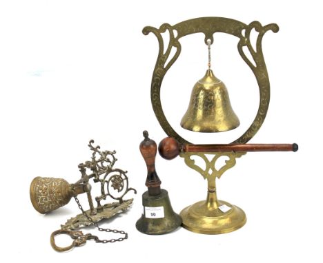 Three 20th century bells. Comprising an Asian example with a stick, a school bell with a wooden handle and a brass example de