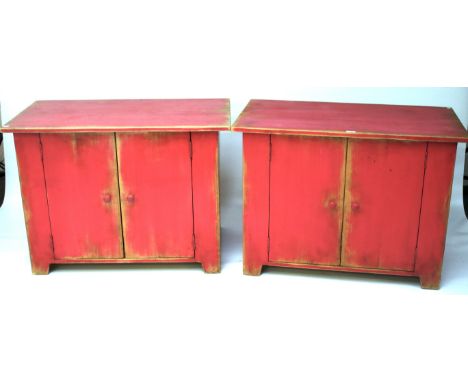 A pair of wooden cabinets. Painted pink with a pair of doors opening to reveal a single shelf, turned supports, raised on bra
