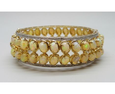 A 925 sterling silver gilt bangle set with over 40cts of Ethiopian opals, 57g