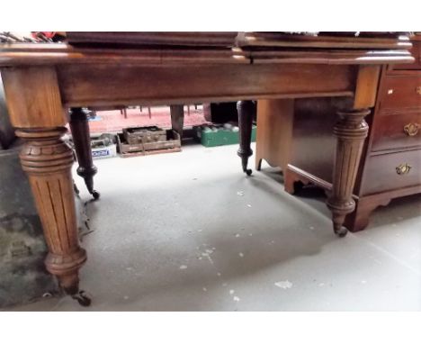 Victorian oak rectangular extending dining table with three extra leaves raised on four turned and fluted legs with ceramic c