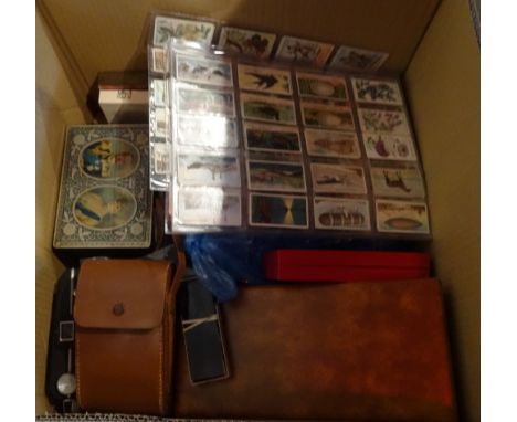 A box containing a quantity of empty first day cover albums, together with cameras, a 1935 Silver Jubilee commemorative tin, 