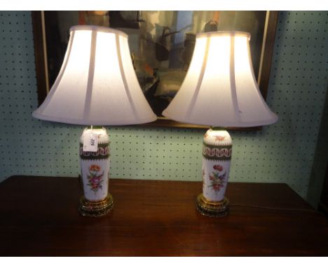 A pair of Continental hand painted ceramic and brass table lamps, each with floral sprays and gilt finish 50cm (to include sh