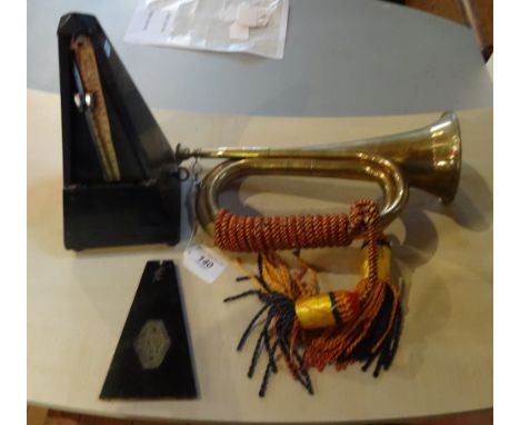 A brass Military bugle, having rope tassel, together with an ebonised wood cased metronome.