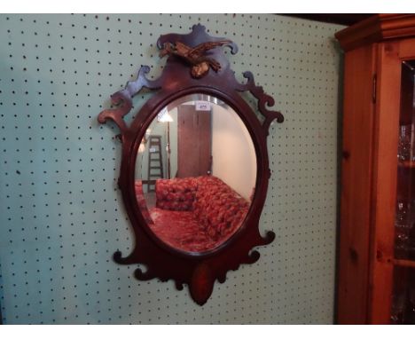 A late Victorian shaped wall mirror, having bevelled edge glass, surmounted by gilt bird with inlaid shell decoration, 42cm x