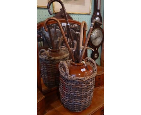 A large stoneware jar in wicker basket, containing a quantity of bone handled and other walking sticks.