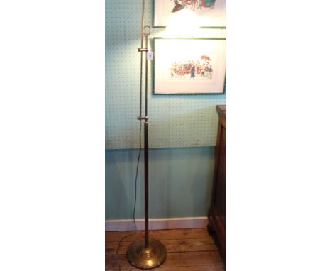 A tall adjustable brass floor standing lamp, with opaque glass shade on circular foot.