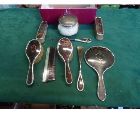 A lady's silver and tortoiseshell mounted dressing table set, comprising: hand mirror, brushes, comb, jar and other items.