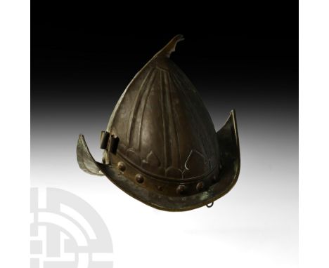 Goa, 16th-17th century AD. A brass helmet with upturned pointed rim, with later finial and frontal plume holder, the bowl div