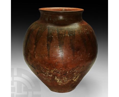 2nd millennium BC. A very large pottery storage vessel with piriform body, waisted neck and everted rim, painted with a circu