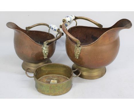 Two Graduated Copper and Brass Helmet Shaped Coal Scuttles with Blue and White Ceramic Handles together with a Brass Two Hand