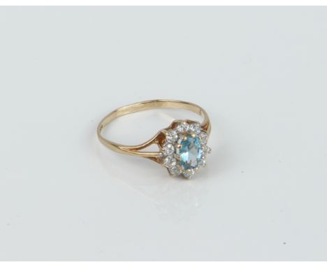 A 9ct yellow gold, topaz and white stone cluster ring - the oval cut 5.5 x 3.75mm topaz within a border of round cut white st