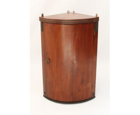 A small bowfront mahogany hanging corner cupboard - early 20th century, with green painted two-shelf interior. (LWH 49 x 37 x