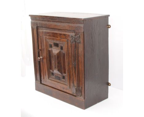 A late-17th or early-18th century oak mural cupboard - the plain top over a chip-carved and channel-moulded frieze, the mitre