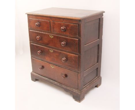 An 18th century oak chest of drawers - the boarded oak top with later edge moulding, over three-panel sides and two short ove