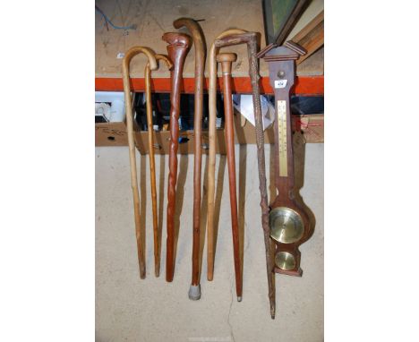 A quantity of walking sticks, barometer and a carved stick.