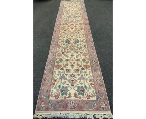 A Persian Sarough runner carpet, woven in subdued tones of pink, turquoise, and cream, 364cm x 82cm. 