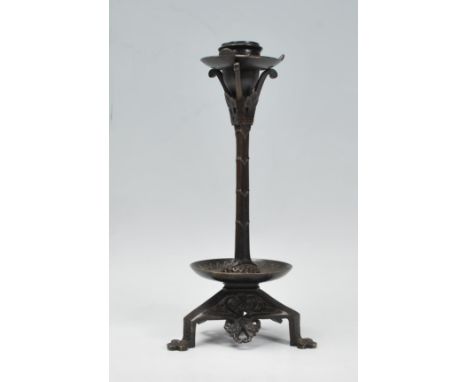 A late 19th / early 20th Century Arts and Crafts case bronzed candlestick raised on a tripod base with scrolled foliate desig