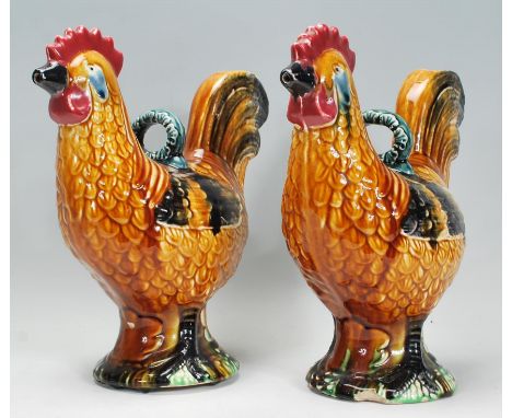 A pair of early 20th Century majolica glazed ceramic water pourers / pitcher jugs in the form of hens, glazed in multiple col