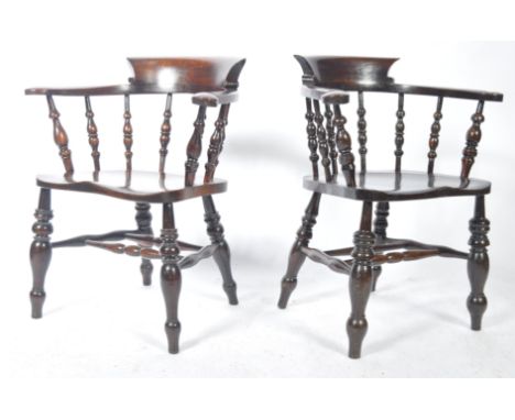 A pair of Victorian 19th century beech and elm wood smokers bow armchairs. Each chair being raised on turned legs united by s