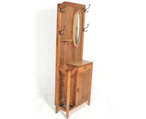 A 1930's Art Deco oak hallstand. The upright back with mirror and hooks over half moon shelf, cupboard, drawer and stick stan