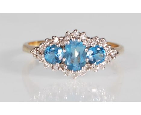 A hallmarked 9ct yellow gold ring set with a central oval faceted cut blue topaz flanked by two round cut blue topaz stones s