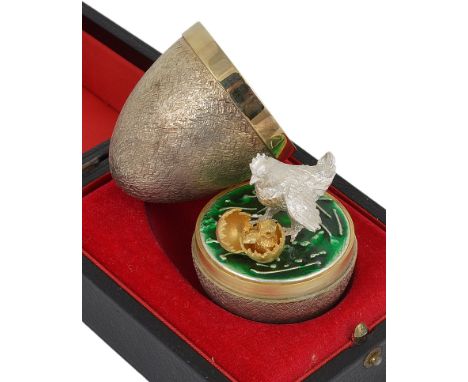 A Silver Gilt Surprise Egg:By Stuart Devlin, London 1981, opening to reveal a chicken standing over a hatching egg, on a gree