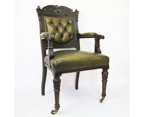 An early Victorian carved and stained mahogany library chair, with button back green leather upholstery, with acanthus leaf d
