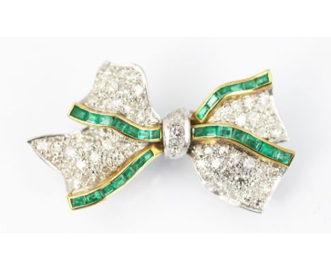 A diamond and emerald set bow brooch, designed as a pavé diamond set ribbon bow, with two rows of channel set emeralds, all s