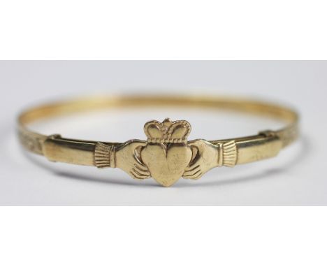 A 9ct yellow gold Claddagh bangle, Birmingham 1991, designed as two hands clasping a central crowned heart, weight 7gms 