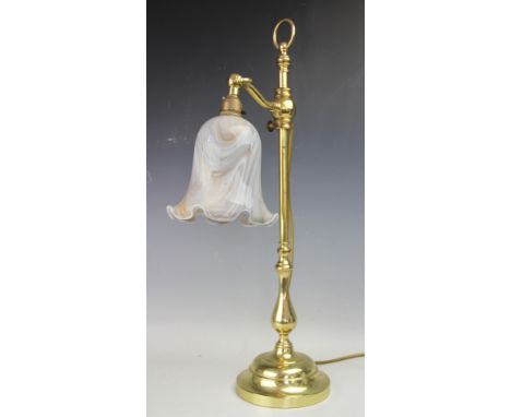 A modern adjustable brass lamp, designed as a single adjustable arm with a crimped rim glass lamp shade, supported by a turne