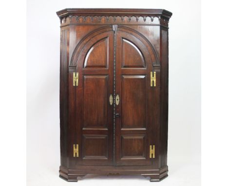 A George III mahogany corner cabinet, with moulded cornice and two arched panelled doors, on bracket feet, 139cm H x 97cm W 