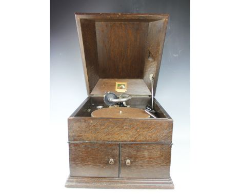 A vintage HMV oak cased record player, with hinged top enclosing record deck, with winder, 35cm high