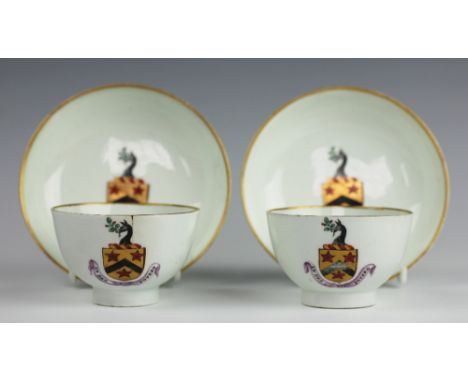 A pair of Lowestoft armorial porcelain tea bowls and saucers, circa 1790, painted in gilt with a coat of arms above a banner 