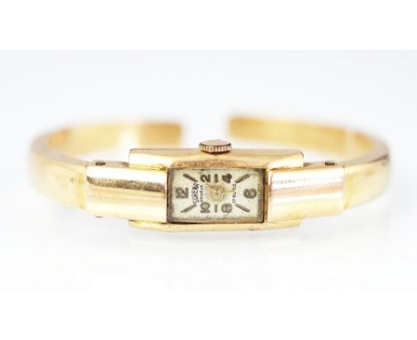 A 'Surena Geneve' ladies wristwatch/bangle, the rectangular face with part Arabic numerals, reverse stamped '18K 750' gross w