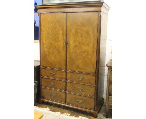 A modern walnut and pine wardrobe, of 18th century design, with moulded cornice above two oval panelled doors with faux drawe