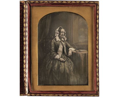 * Dagurreotype. Large half-plate daguerreotype of a lady seated at a table, c. 1855, lightly hand-tinted, 16 x 12cm, full lea