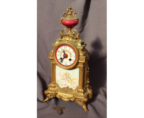 A 19th century French gilt metal mantle clock, with an urn finial decorated with grapes and leaves on four splayed feet, the 