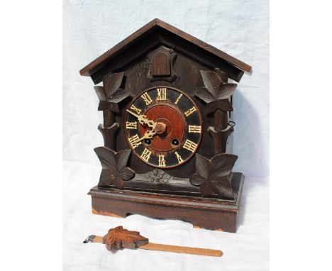 A Black forest cuckoo mantle clock with a pitched roof, carved leaf sides and a plinth base, the dial with Roman numerals str