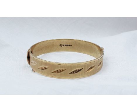 A 9ct yellow gold hinged bangle, with line and leaf decoration, approximately 29 grams