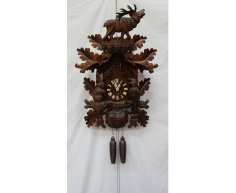 A modern Black Forest Cuckoo clock, with a roaring stag and leaf surmount, the clock carved with a rabbit, bird and bag, come