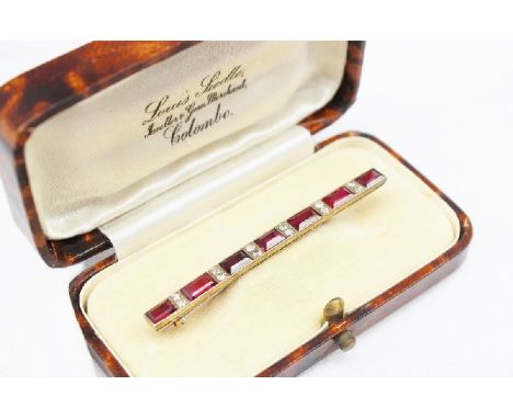 A ruby and diamond bar brooch, set with six baguette cut rubies and twelve old cut diamonds to a yellow metal setting 5.3cm l