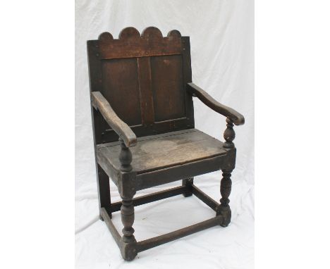 An 18th century oak wainscott chair, the shaped panel back above a planked seat on turned legs united by stretchers