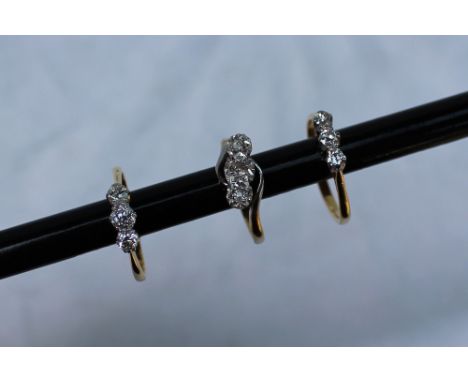 A three stone diamond ring set with graduated old cut diamonds to a white metal claw setting and a yellow metal shank marked 