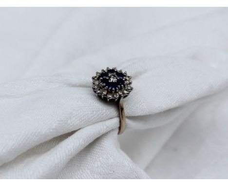 A sapphire and diamond dress ring, set with a central round brilliant cut diamond approximately 0.1 of a carat, surrounded by