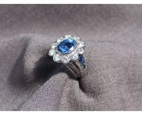 A sapphire and diamond cluster ring, the central sapphire measuring approximately 10mm by 8mm, surrounded by ten brilliant cu