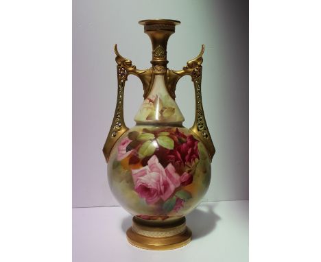 A Royal Worcester porcelain twin handled vase with a pair of pierced gilt decorated handles, the body painted with roses and 
