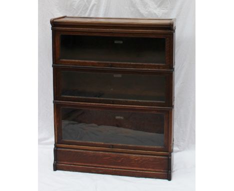 An oak Globe-Wernicke Co. three section bookcase with glazed up and over doors on a plinth base, 86.5cm wide x 27cm deep x 11